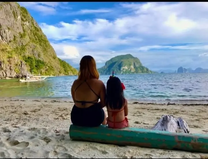 Two guests sitting on a log, looking out at the islands
