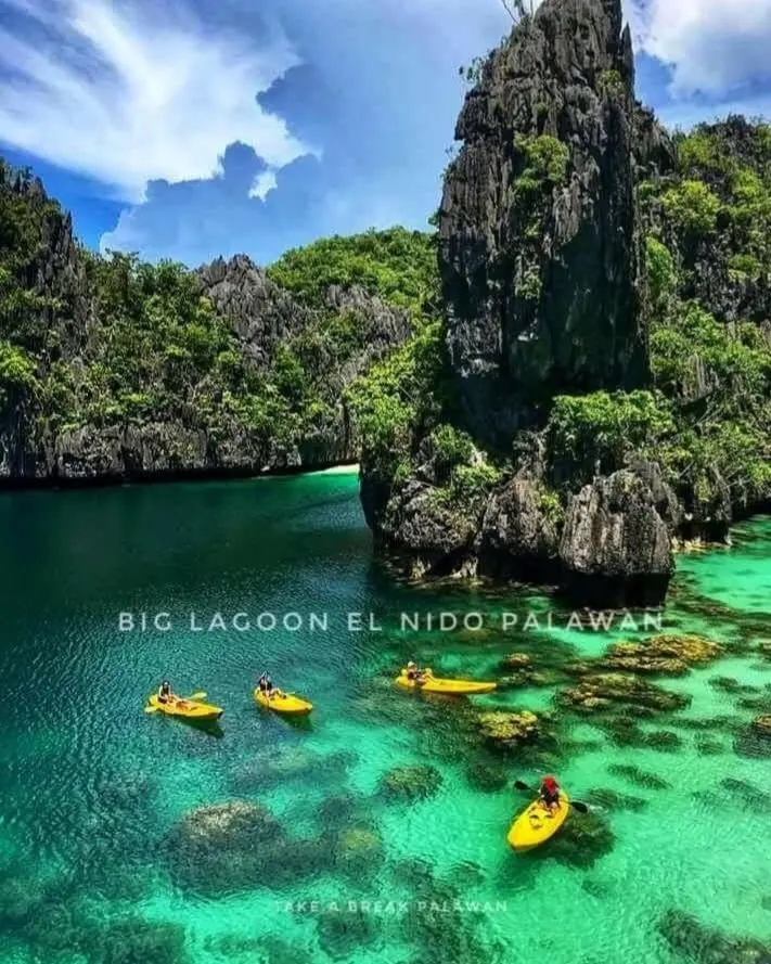 Kayaks on the green water of Big Lagoon, El Nido, between limestone walls