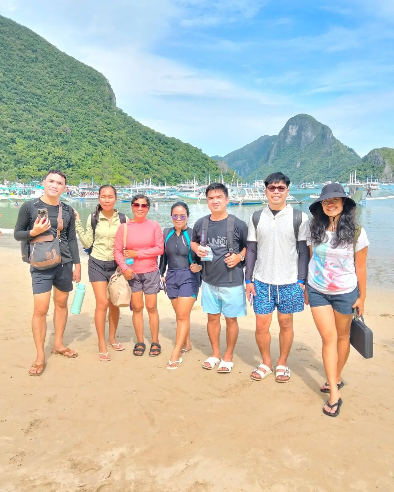 A tour group on the beach with green islands behind