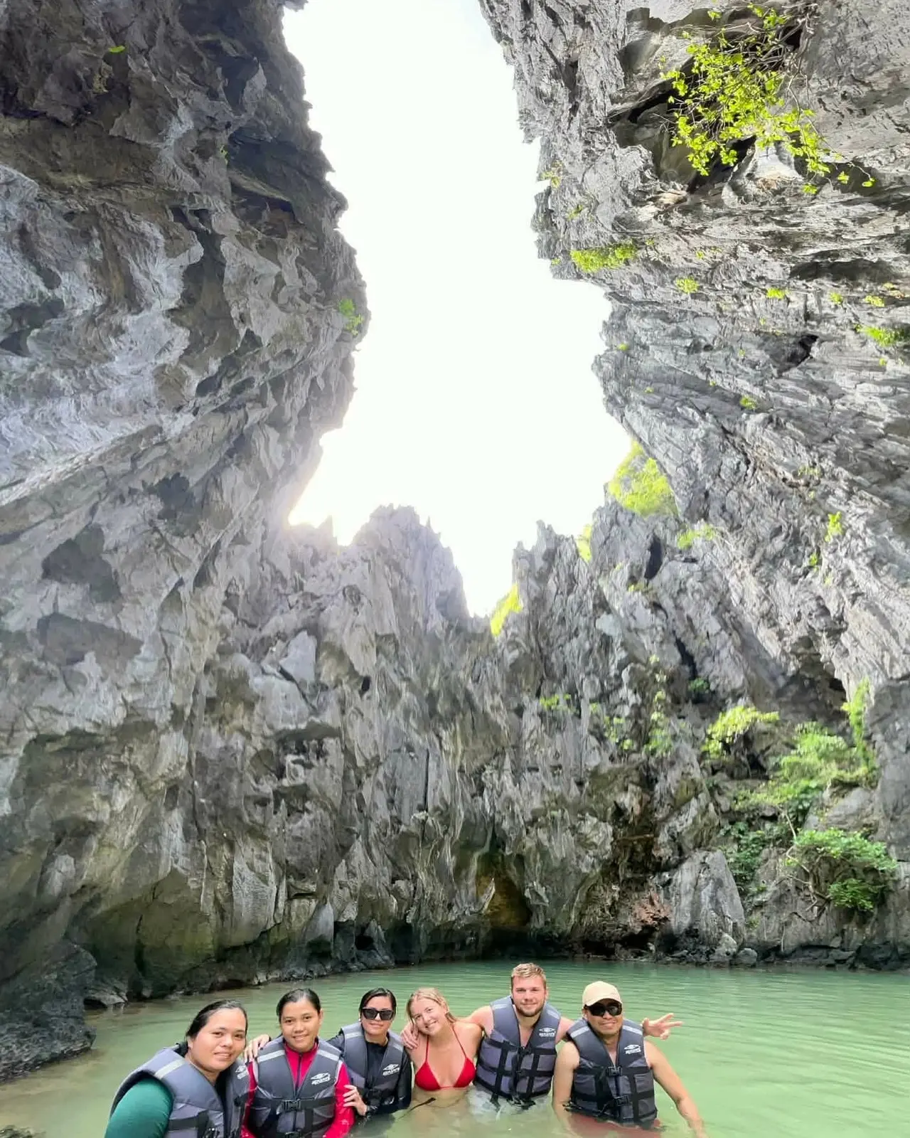 Guests in a lagoon looking up at towering cliffs and sky