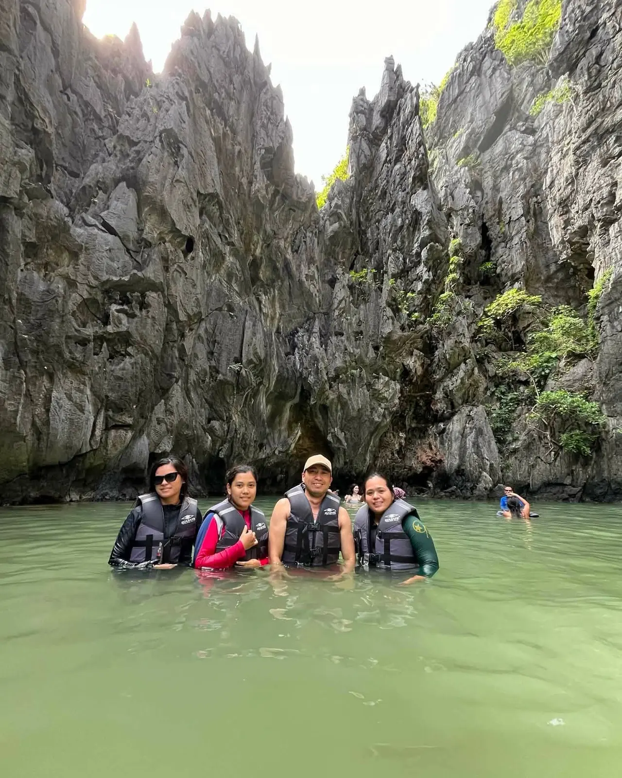 Guests in life vests swimming in a lagoon below grey limestone walls