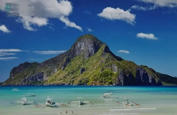 A tall green island rising from clear shallow water off El Nido