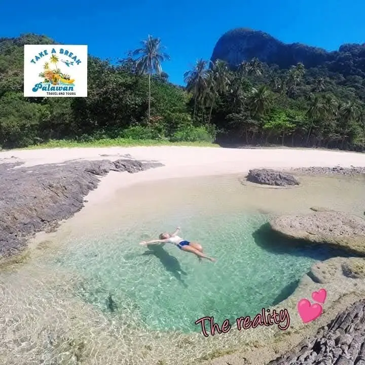 A guest floating in a clear rock pool beside a white beach